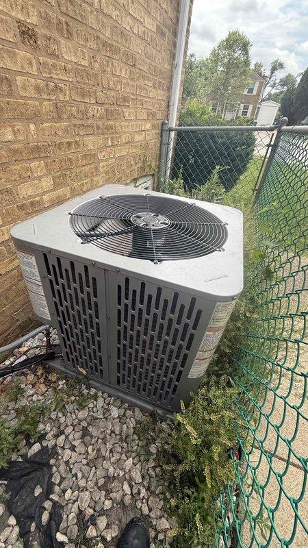 Responded to service call for outdoor condensing unit with reported ice formation and non-spinning fan. Upon inspection, confirmed blower wheel assembly was not operating properly despite unit being approximately one year old. Performed diagnostic assessment of both indoor blower motor assembly and outdoor condenser unit, documenting equipment condition with photographic evidence showing blower wheel/squirrel cage fan configuration and exterior condenser installation on gravel pad against building exterior.
