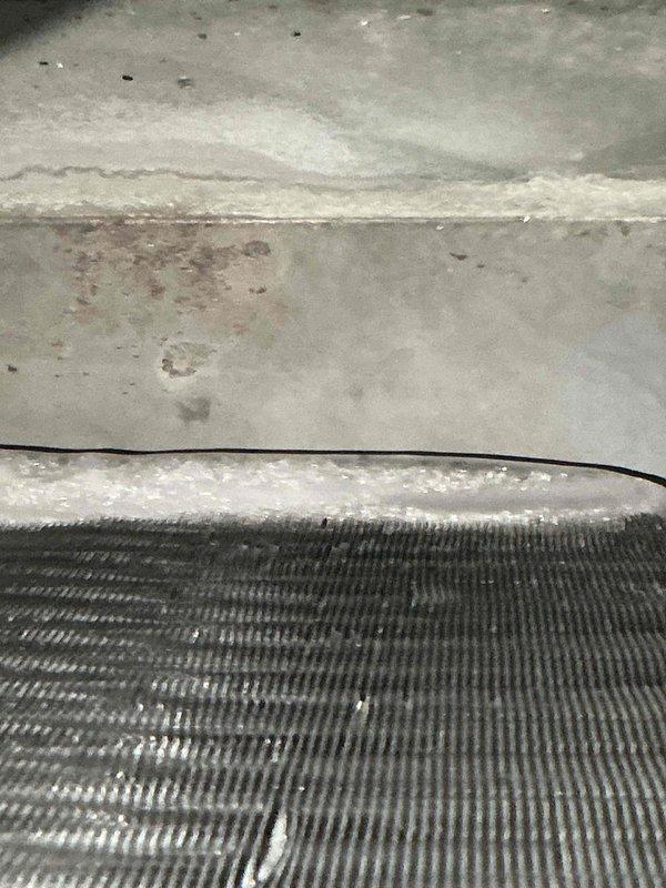 Responded to service call for commercial rooftop air conditioning unit producing loud mechanical noises described as "bowling balls" inside the system. Upon arrival, conducted visual inspection of multiple rooftop condenser units and identified significant frost and ice accumulation on evaporator coil, indicating restricted airflow or low refrigerant charge. Documented equipment condition with photographs showing crystalline ice buildup along coil edges and potential airflow obstruction. System requires further diagnostic testing to determine root cause of noise complaint and address refrigerant system abnormalities affecting cooling performance.