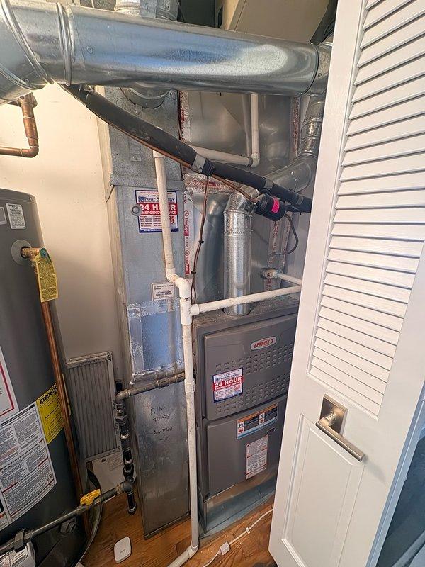 Responded to service call for reported water leak in HVAC duct system causing ceiling mold growth. Performed diagnostic inspection of residential utility closet housing furnace, water heater, and associated ductwork. Identified water damage and staining on ceiling near HVAC equipment, with visible discoloration indicating active moisture intrusion. Inspected galvanized steel plenum, ductwork transitions, and condensate drainage system for leak sources. Documented equipment conditions and leak evidence with photographs. Provided customer with flat-rate repair options to address leak source and prevent further water damage, allowing mold remediation to proceed safely.