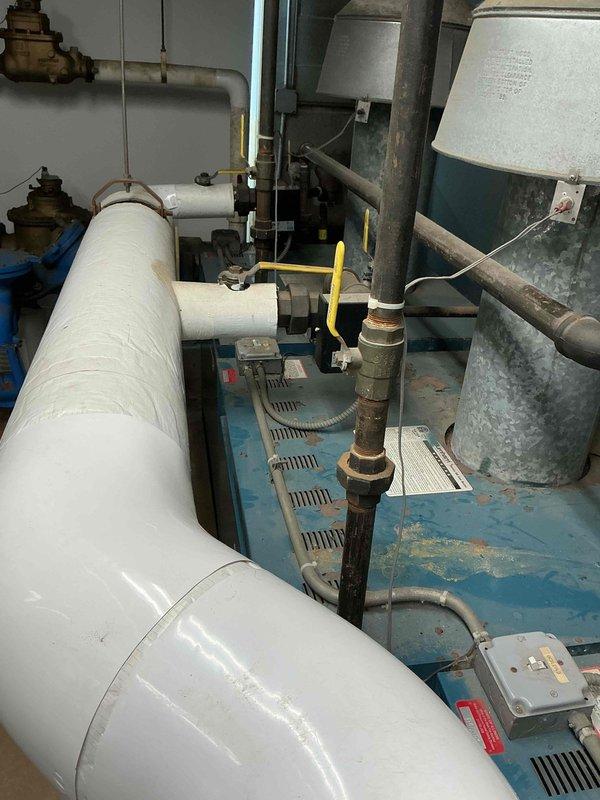 Replaced box mount transformer on central heating boiler 2 and completed startup testing. Repaired damaged 10" flue pipe and elbow on domestic hot water boiler 2. Removed boiler hood and burner assembly to perform heat exchanger washdown. Replaced pressure relief valve. Reversed staging sequence on domestic hot water boilers to establish boiler 1 as primary first stage unit. Conducted full system startup, operational testing, and flue temperature verification upon completion of all repairs.