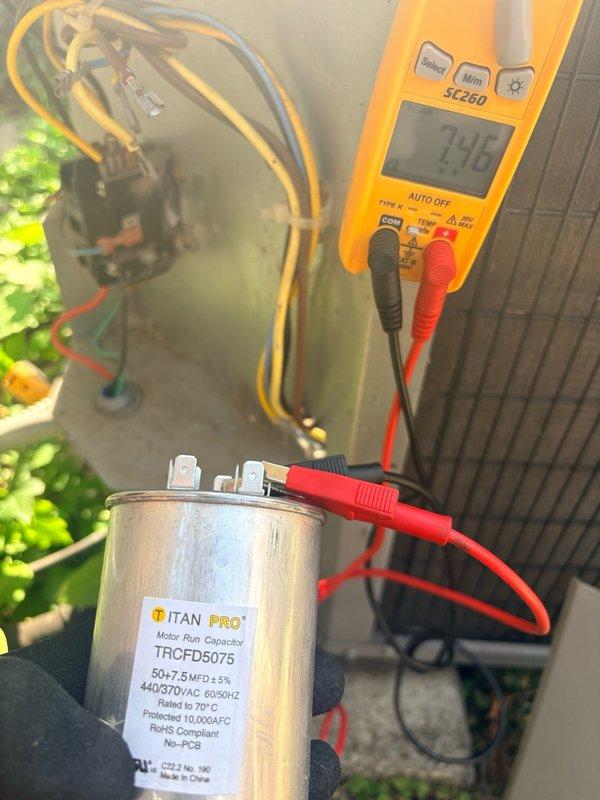Responded to no cooling call for new customer. Performed diagnostic testing on outdoor condensing unit and identified failed dual-run capacitor (TRCFD5075, 50+7.5 MFD). Verified capacitor failure using digital multimeter, which showed significantly degraded capacitance reading of 7.48 microfarads. Replaced defective TITAN PRO motor run capacitor with new unit rated at 440/370VAC. Tested system operation, confirmed proper compressor and condenser fan motor function. Recorded all equipment information and discussed preventative maintenance options with customer. System restored to normal cooling operation.