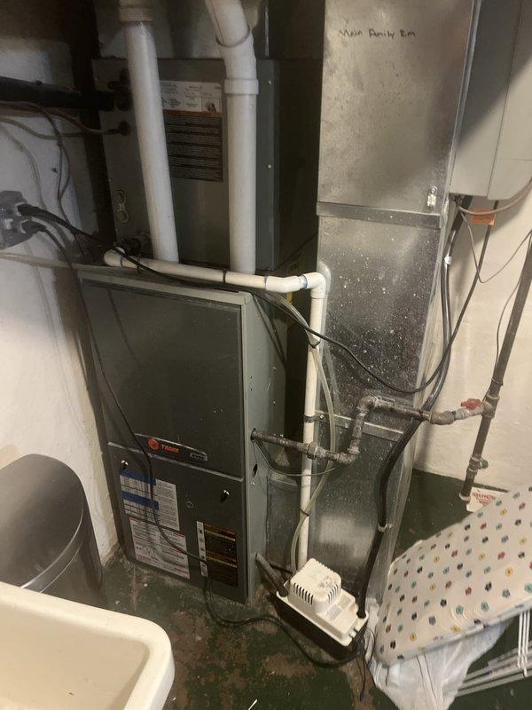 Conducted comprehensive assessment of existing Trane furnace and air conditioning system for replacement estimate in residential basement utility room. Evaluated current HVAC equipment configuration including gas furnace with PVC intake/exhaust venting, ductwork system serving multiple zones including main family room, and associated components. Documented equipment specifications, photographed existing installation layout, and assessed mechanical room space constraints for proper replacement unit sizing and installation planning.