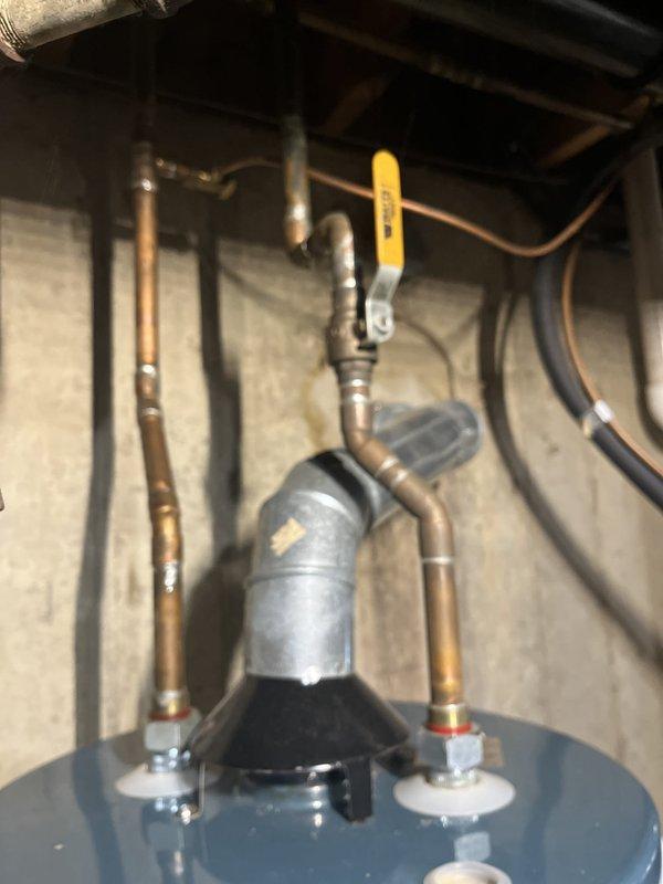 Responded to service call for non-operational water heater in basement utility area. Upon inspection, confirmed existing unit was a power vent model requiring replacement. Assessed installation site, documenting current configuration including metallic exhaust vent pipe, copper supply lines, yellow-handled ball valve, and associated plumbing connections. Evaluated utility room setup with concrete block walls, existing piping infrastructure, and adjacent water treatment equipment. Prepared comprehensive estimate for power vent water heater replacement including removal of existing unit, installation of new comparable power vent model, connection of hot and cold water supply lines, proper venting configuration, and all necessary fittings and materials to complete installation per code requirements.