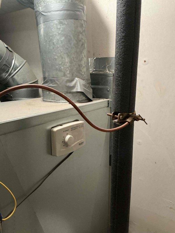 Completed comprehensive maintenance on residential HVAC system including air conditioning unit and furnace for customer who recently moved into property. Performed standard tune-up procedures on both systems, documented equipment conditions with photographs showing indoor furnace installation with associated piping and controls, as well as outdoor condensing unit. Noted significant rust and corrosion on outdoor cylindrical component and weathering on concrete pad, with condensation present on indoor ductwork indicating system operation.