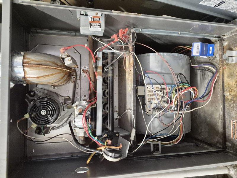 Responded to no heat call on residential HVAC system approximately 15-18 years old. Upon inspection, diagnosed failed 3/4 HP blower motor preventing system operation. Removed access panel and performed visual inspection revealing significant rust staining on blower housing and accumulated debris throughout cabinet. Motor exhibited no operational function and required replacement. Provided customer with replacement options and discussed system age considerations. Unit interior showed typical wear patterns consistent with age, including dust accumulation and oxidation on metal surfaces. Customer advised of repair requirements and given recommendation to contact management regarding potential system replacement given advanced age of equipment.