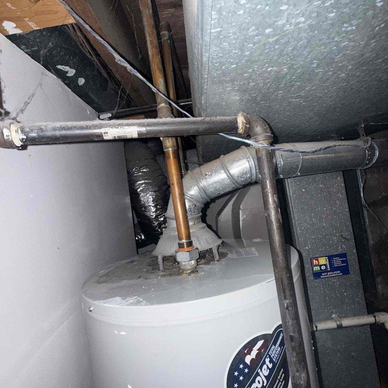 Responded to service call for leaking water heater. Upon arrival, performed comprehensive inspection of tanked water heater system and surrounding plumbing connections. Identified source of leak and assessed condition of unit, piping, and associated components. Documented equipment condition through photographs showing water heater installation, copper and galvanized piping connections, and evidence of moisture on concrete floor surface. Evaluated all pipe joints, fittings, and connections for integrity. Provided assessment and recommendations for necessary repairs to resolve active leak condition.