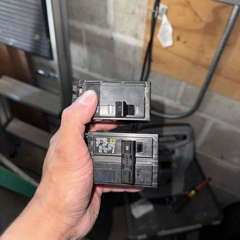 Returned to site to complete warranty work by replacing defective circuit breaker for AC unit. Removed worn 200-amp main breaker from electrical panel and installed new QOM2200VH breaker rated at 22,000A interrupting capacity, 120/240V AC. Verified proper electrical connections, tested breaker operation, and confirmed AC system functionality upon completion.