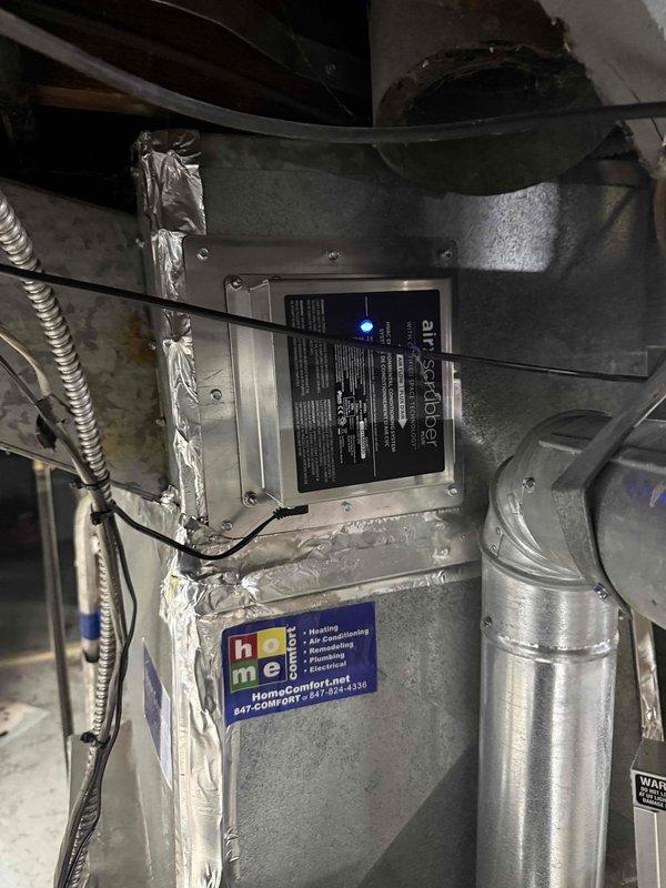 Replaced existing air scrubber unit on HVAC system. Removed old air purification device and installed new air scrubber assembly onto furnace plenum, securing all connections with proper ductwork attachments and metallic tape. Verified electrical connections to control board, confirmed LED indicator light functioning properly, and tested system operation to ensure proper air filtration performance.