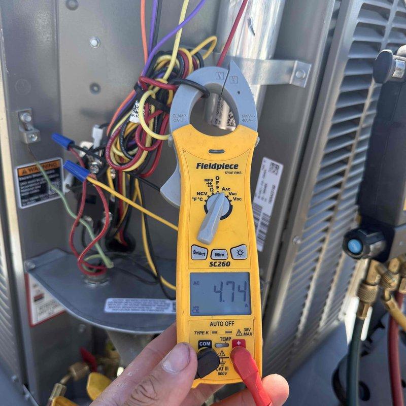 # Warranty Callback - Frozen Evaporator Coil

Responded to warranty callback for recently installed unit experiencing freeze-up conditions. Customer had switched system to fan-only mode to address icing, but ice remained present on coil. Performed diagnostic evaluation using Fieldpiece SC260 clamp meter to measure electrical parameters and SMAN refrigerant manifold with micron gauge to assess system pressures and temperatures across both high and low sides. Readings indicated abnormal operating conditions contributing to ice formation. Documented equipment conditions with photographs showing diagnostic tool measurements and system configuration. Verified issue was related to original installation parameters. Made necessary adjustments to resolve freeze-up condition and restore proper system operation under warranty coverage.