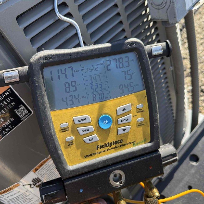 # Warranty Callback - Frozen Evaporator Coil

Responded to warranty callback for recently installed unit experiencing freeze-up conditions. Customer had switched system to fan-only mode to address icing, but ice remained present on coil. Performed diagnostic evaluation using Fieldpiece SC260 clamp meter to measure electrical parameters and SMAN refrigerant manifold with micron gauge to assess system pressures and temperatures across both high and low sides. Readings indicated abnormal operating conditions contributing to ice formation. Documented equipment conditions with photographs showing diagnostic tool measurements and system configuration. Verified issue was related to original installation parameters. Made necessary adjustments to resolve freeze-up condition and restore proper system operation under warranty coverage.