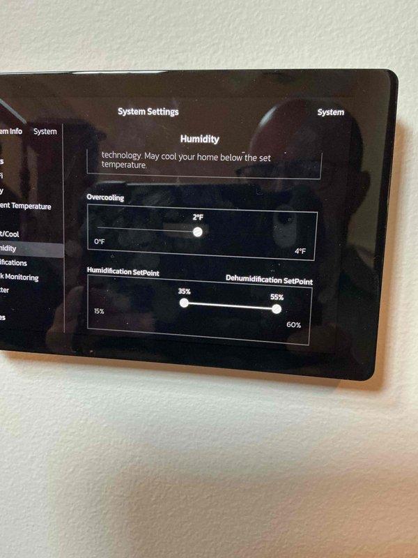 Responded to warranty callback regarding inconsistent humidity readings on newly installed Lennox thermostat displaying 70%+ humidity despite dehumidification setpoint of 55%. Accessed System Settings and verified dehumidification control was set to Climate IQ (Auto) mode with overcooling parameter configured at 2°F. Confirmed humidification and dehumidification setpoints were properly programmed at 35% and 55% respectively. Explained that thermostat reading variance compared to other household sensors (upstairs unit at 62%, third-party sensor at 58.4%) falls within acceptable calibration tolerances and that Climate IQ technology automatically adjusts system operation based on local climate conditions.