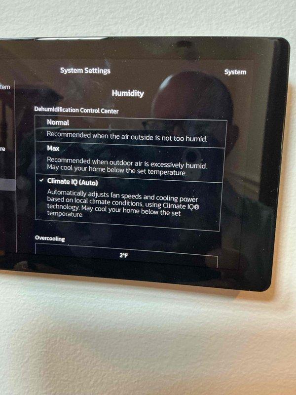Responded to warranty callback regarding inconsistent humidity readings on newly installed Lennox thermostat displaying 70%+ humidity despite dehumidification setpoint of 55%. Accessed System Settings and verified dehumidification control was set to Climate IQ (Auto) mode with overcooling parameter configured at 2°F. Confirmed humidification and dehumidification setpoints were properly programmed at 35% and 55% respectively. Explained that thermostat reading variance compared to other household sensors (upstairs unit at 62%, third-party sensor at 58.4%) falls within acceptable calibration tolerances and that Climate IQ technology automatically adjusts system operation based on local climate conditions.