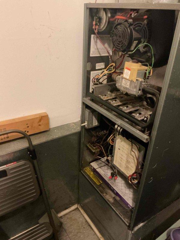 Responded to service call for non-operational air conditioning system on 30-year-old unit. Upon arrival, coordinated access with on-site tenant and performed diagnostic assessment of HVAC system. Inspected Honeywell Chronotherm III programmable thermostat, verifying display functionality and temperature settings. Evaluated indoor furnace unit, examining blower assembly, gas valve controls, wiring connections, and heat exchanger components. Documented system conditions with photographic evidence showing thermostat interface and internal furnace cabinet components including electrical connections, control modules, and mechanical assemblies for service records.