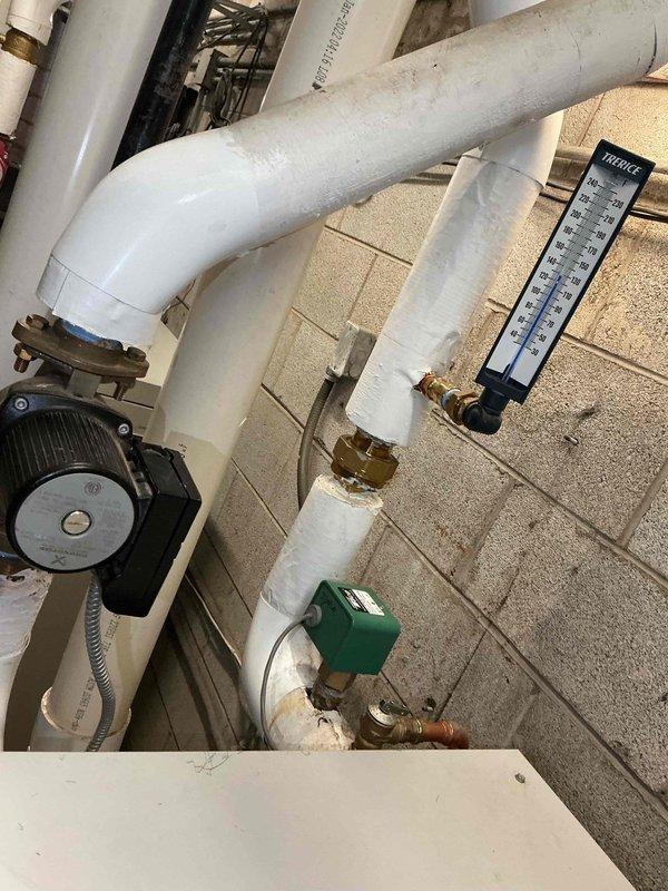 Responded to no hot water complaint at commercial property. Inspected hot water circulation system including PVC piping, circulation pump, thermometer, and brass valve connections. Coordinated with office to contact property management for approval to proceed with necessary repairs. Documented system conditions with photographs showing circulation pump assembly, piping configuration, and prepared tools for service work.