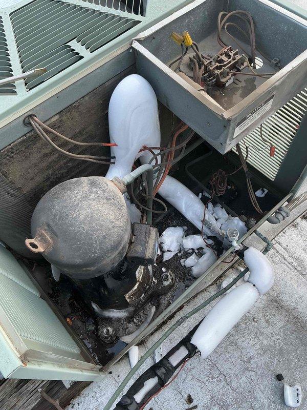 Responded to no cooling complaint on 10+ year old rooftop HVAC system. Upon arrival, tenant reported frozen evaporator coil with supporting photos. Inspected indoor furnace unit and found blower motor producing screeching noise while maintaining proper airflow and RPM. Attempted to access rooftop condenser unit for complete system diagnosis but required building management authorization for roof access. Photographed accessible rooftop equipment showing weathered condenser unit with exposed compressor, refrigerant lines, electrical junction box, and condenser coils exhibiting signs of age and outdoor exposure. Unable to complete full system evaluation or perform refrigerant charge testing due to access restrictions. Recommended return visit once roof access is approved to diagnose root cause of frozen coil condition, inspect condenser operation, check refrigerant levels, and address blower motor noise issue.