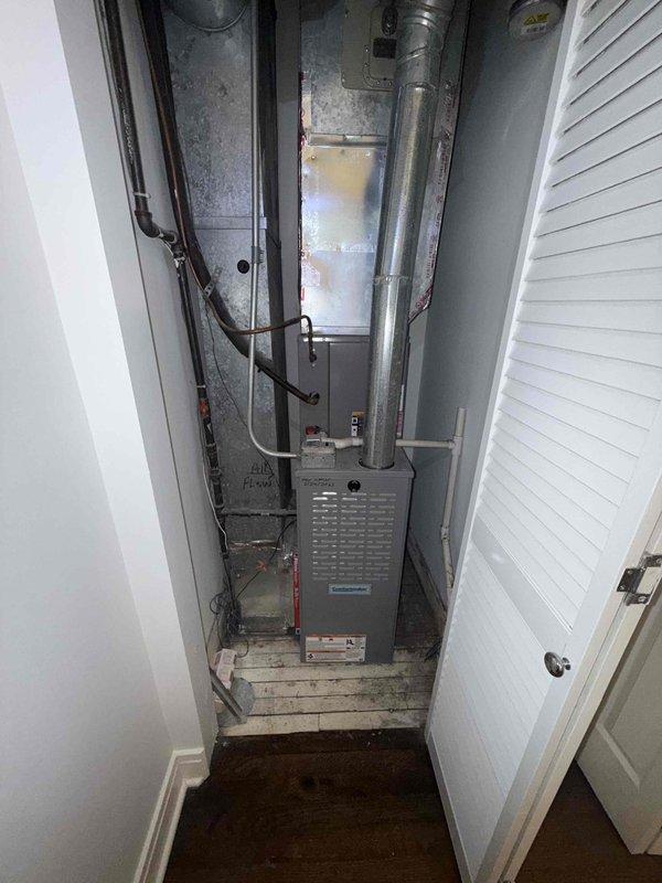 Completed new customer estimate for residential HVAC system located in utility closet. Documented existing equipment with photographs showing furnace unit with gray metal casing, overhead air handler with ductwork, and refrigerant lines along wall. Inspected control board and internal components, noting normal wear and service condition. Collected payment and entered equipment information into service system.
