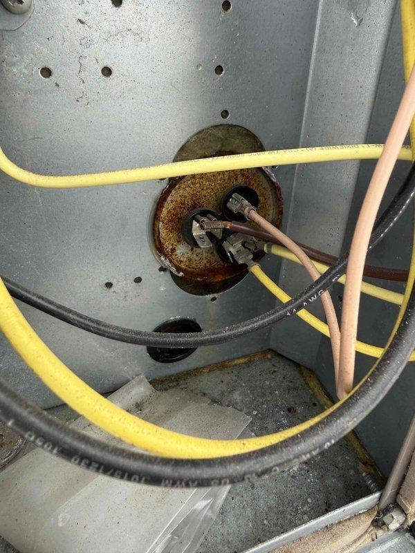 Responded to no cooling complaint for commercial office space. Accessed rooftop packaged HVAC unit and performed diagnostic evaluation. Inspected electrical panel and discovered corroded wire entry point with deteriorated grommet where multiple conductors pass through enclosure. Documented equipment condition including rust around penetration point and wiring connections. Coordinated with office for approval process through property management before proceeding with repairs.