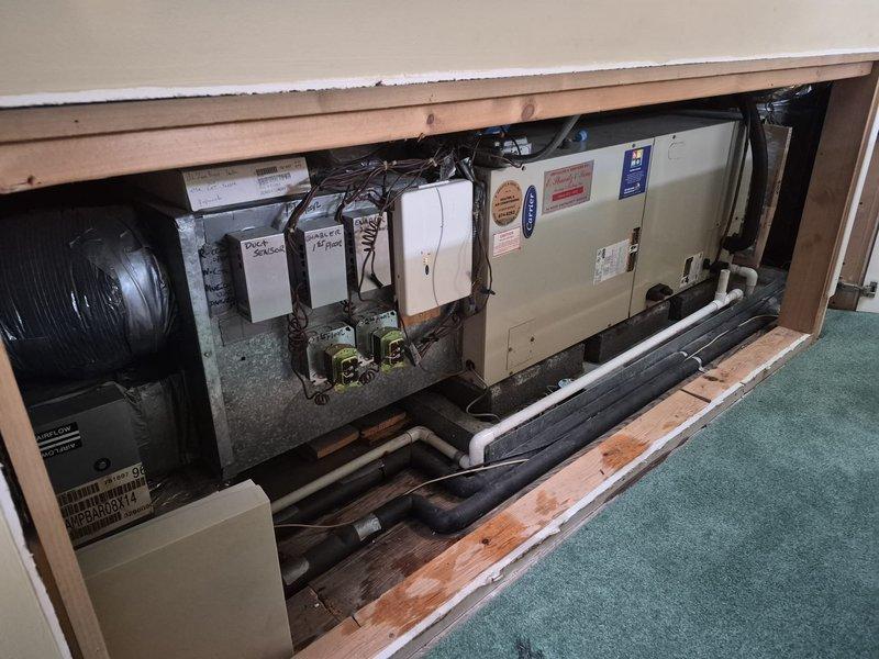 # HVAC Maintenance Call Back - Air Handler Diagnostic

Returned to service location to address ongoing air handler malfunction reported after previous service visit. Upon arrival, accessed floor cavity to inspect air handler unit, control panels, and associated electrical components. Performed comprehensive diagnostic evaluation of black cylindrical air handler unit and white electrical control boxes to identify source of continued operational issues.

Inspected refrigerant lines, monitoring gauges, and electrical connections in mechanical space. Verified proper installation of foam-insulated refrigerant lines and checked gauge readings for system pressures. Examined control wiring, ductwork connections, and PVC condensate drain routing. Documented equipment configuration and current system status with photographs for service records.

System remains under observation to determine root cause of recurring air handler performance issues. Further diagnostic work or component replacement m