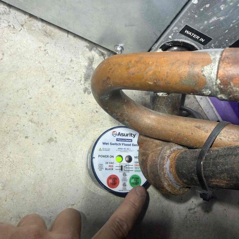 Installed Asurity wet switch flood detector in basement utility area to provide water detection and system protection. Connected device to 24 VAC power supply and wired into existing HVAC control board using proper terminal connections. Mounted detector near floor level adjacent to copper plumbing lines to monitor for potential water leaks or flooding conditions. Verified proper operation of wet switch by testing alarm and reset functions. All electrical connections secured and system confirmed operational upon completion.
