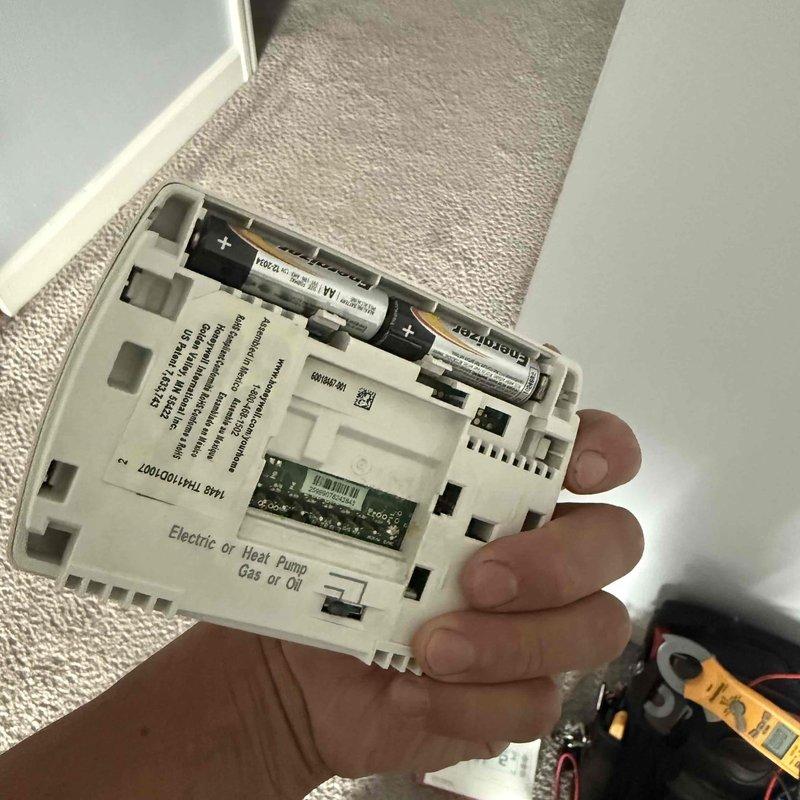 Responded to service call for Honeywell thermostat reported as non-operational despite tenant replacing batteries. Upon arrival, removed thermostat from wall mount and inspected internal components including battery compartment and circuit board. Verified fresh Energizer batteries were properly installed and examined connections to ensure proper contact. Diagnosed thermostat malfunction, tested system communication with American Standard furnace and humidifier equipment located in basement utility area, and restored heating system operation.