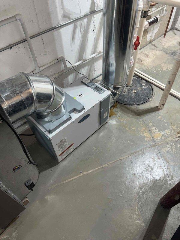 Responded to service call for dehumidifier leaking red fluid in basement mechanical room. Upon arrival, found significant pooling of rust-colored water on floor around base of HVAC system and cylindrical ductwork. Inspection revealed extensive corrosion and rust streaking on metal components, with discolored liquid accumulating on concrete floor. Documented equipment condition and water damage with photographs showing affected areas, corroded surfaces, and extent of leakage. Collected standard diagnostic fee and discussed repair options with customer.