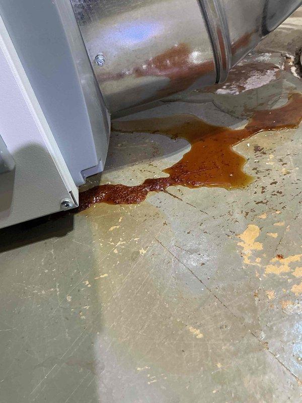 Responded to service call for dehumidifier leaking red fluid in basement mechanical room. Upon arrival, found significant pooling of rust-colored water on floor around base of HVAC system and cylindrical ductwork. Inspection revealed extensive corrosion and rust streaking on metal components, with discolored liquid accumulating on concrete floor. Documented equipment condition and water damage with photographs showing affected areas, corroded surfaces, and extent of leakage. Collected standard diagnostic fee and discussed repair options with customer.