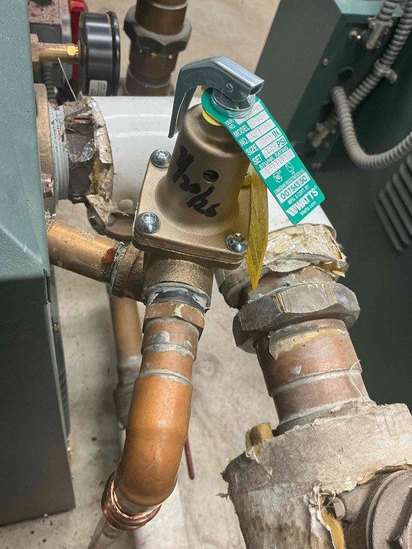 Responded to inspection concern regarding pressure relief valve installation on domestic hot water system versus heating boiler. Documented and photographed both the DHW pressure relief valve assembly with copper piping connections and the complete heating boiler unit to verify proper valve placement and specifications for inspector review and approval.