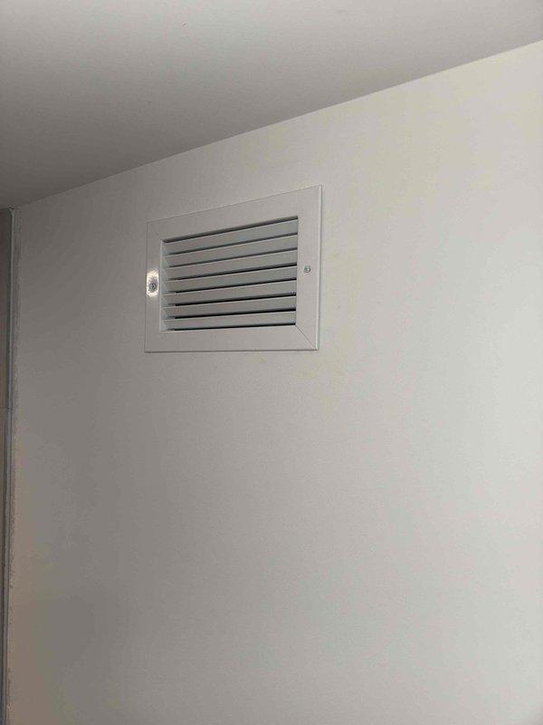 Completed installation of bathroom exhaust ventilation system. Installed new exhaust vent with grille on interior wall and corresponding ceiling register with horizontal louvers for proper air circulation. Both components secured and operational, providing adequate ventilation for the bathroom space.