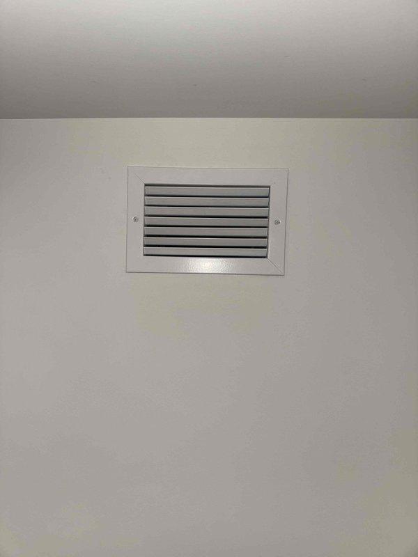 Completed installation of bathroom exhaust ventilation system. Installed new exhaust vent with grille on interior wall and corresponding ceiling register with horizontal louvers for proper air circulation. Both components secured and operational, providing adequate ventilation for the bathroom space.