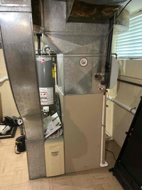 Responded to no cooling complaint on residential HVAC system aged 10+ years. Upon arrival, performed diagnostic evaluation of furnace and air conditioning system located in basement utility area. Conducted visual inspection of equipment, ductwork, and associated components. Documented system configuration including furnace unit, metal ductwork distribution, and connected water heater. Assessed overall condition of aging HVAC equipment and identified potential service needs. Photographed installation for records and further evaluation of system components and infrastructure.