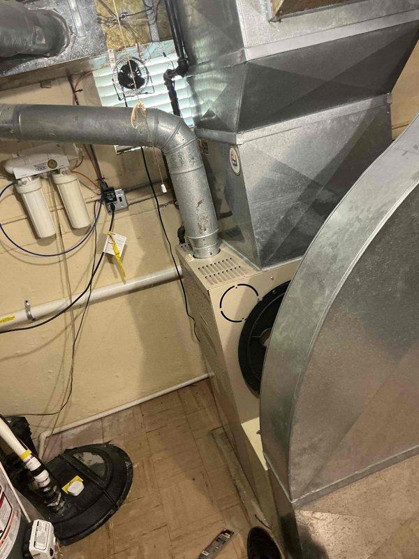 Responded to no cooling complaint on residential HVAC system aged 10+ years. Upon arrival, performed diagnostic evaluation of furnace and air conditioning system located in basement utility area. Conducted visual inspection of equipment, ductwork, and associated components. Documented system configuration including furnace unit, metal ductwork distribution, and connected water heater. Assessed overall condition of aging HVAC equipment and identified potential service needs. Photographed installation for records and further evaluation of system components and infrastructure.