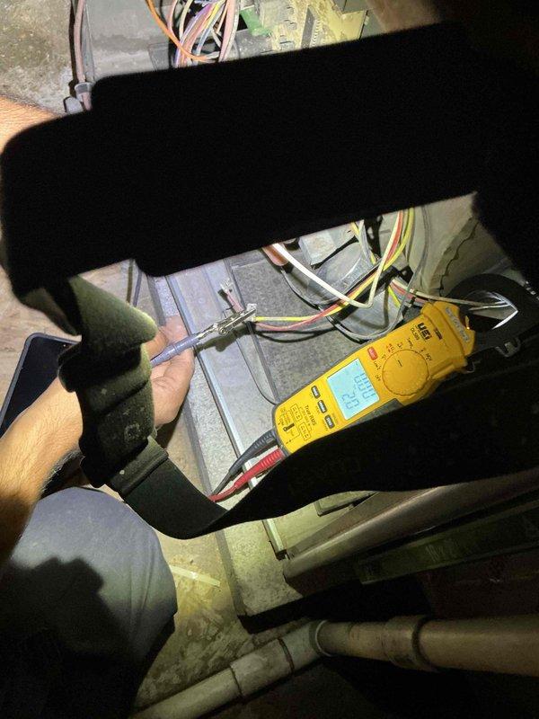 Responded to service call for intermittent electrical issues where HVAC unit was reportedly causing power surges and tripping circuit breaker. Upon arrival, accessed unit in confined mechanical space and performed comprehensive electrical diagnostics using digital multimeter. Tested voltage, amperage, and continuity across multiple electrical components and connection points within the system. Evaluated wire harnesses, junction box connections, and electrical panel to identify potential sources of electrical faults causing circuit breaker trips. Documented findings with photographs showing testing procedures and electrical components. Coordinated with office regarding approval process for continued diagnostics and repairs, as building management authorization was required to proceed with additional work on commercial property.