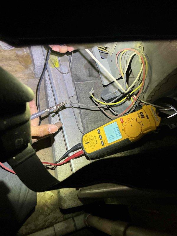 Responded to service call for intermittent electrical issues where HVAC unit was reportedly causing power surges and tripping circuit breaker. Upon arrival, accessed unit in confined mechanical space and performed comprehensive electrical diagnostics using digital multimeter. Tested voltage, amperage, and continuity across multiple electrical components and connection points within the system. Evaluated wire harnesses, junction box connections, and electrical panel to identify potential sources of electrical faults causing circuit breaker trips. Documented findings with photographs showing testing procedures and electrical components. Coordinated with office regarding approval process for continued diagnostics and repairs, as building management authorization was required to proceed with additional work on commercial property.