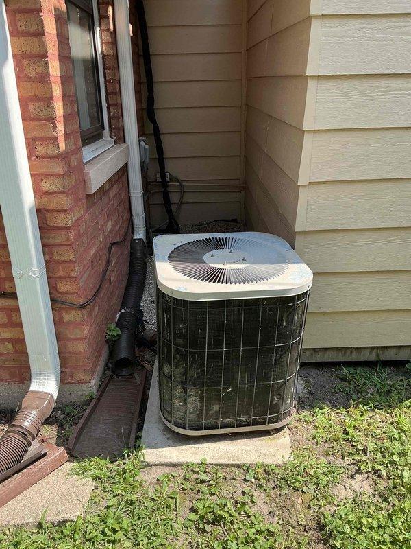Responded to service call for water leak at furnace system. Upon inspection, identified leaking PVC condensate drain piping connected to furnace with compromised purple primer joints at T-fitting connection. Documented existing outdoor condensing unit condition and indoor furnace piping configuration. Assessed PVC drainage system for proper slope and connection integrity at T-junction fitting where active leak was occurring.