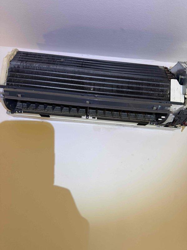 Responded to callback for wall-mounted AC unit experiencing recurring water leakage issue. Removed front panel to access internal components and inspected evaporator coil assembly and drainage system. Measured supply air temperature at 59.5°F to verify cooling operation and assess system performance during diagnostic evaluation.
