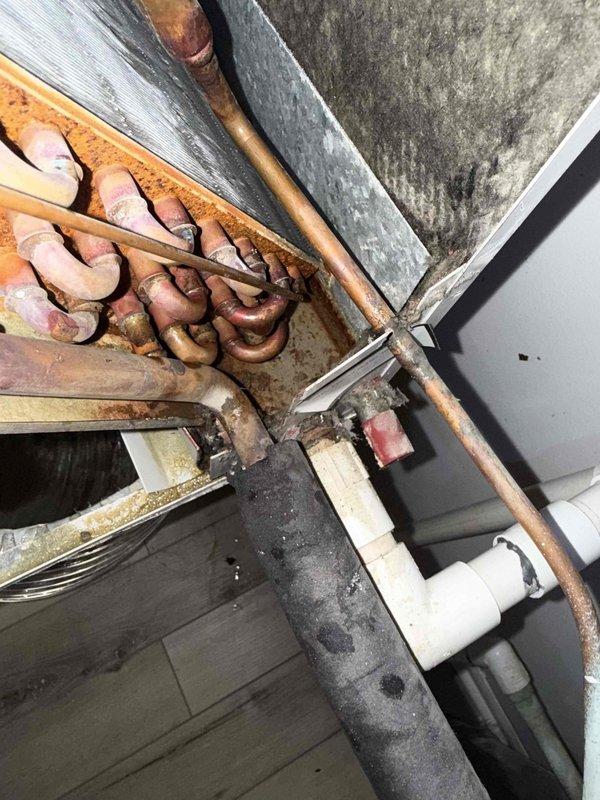 Responded to service call for water leak at air handler. Upon arrival, confirmed rusted condensate drain pan beneath furnace with active condensation leakage, initially discovered by plumber during drain line service. Inspected HVAC system and photographed oxidized copper refrigerant lines, ductwork connections, and drainage components. Documented heavily soiled flexible ductwork with significant dust and debris accumulation. Assessed air handler installation showing age-related deterioration of drain pan and surrounding mechanical components. Provided customer with diagnostic findings regarding failed condensate pan requiring replacement to prevent continued water damage. Discussed repair options and presented recommendations for drain pan replacement and system maintenance.
