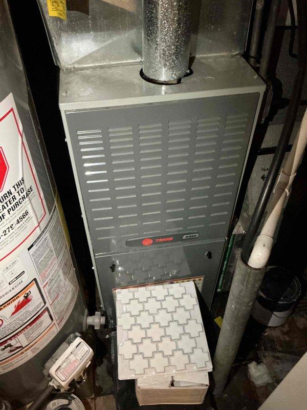 Responded to service call for water accumulation beneath furnace at residential property. Upon arrival, inspected Trane XV95 furnace installation and surrounding mechanical room area. Conducted thorough examination of condensate drainage system, including white PVC condensate lines, drain trap, and discharge piping. Checked for potential sources of water leakage including condensate pump operation, drain line blockages, and proper pitch of drainage pipes. Verified furnace operation and inspected heat exchanger for signs of leakage. Examined water heater proximity to furnace to rule out cross-contamination from plumbing fixtures. Assessed air filter condition and verified proper airflow through system. Inspected all visible piping connections, joints, and elbows for signs of moisture or active leaking. Documented system configuration and equipment condition with photographs for service records.