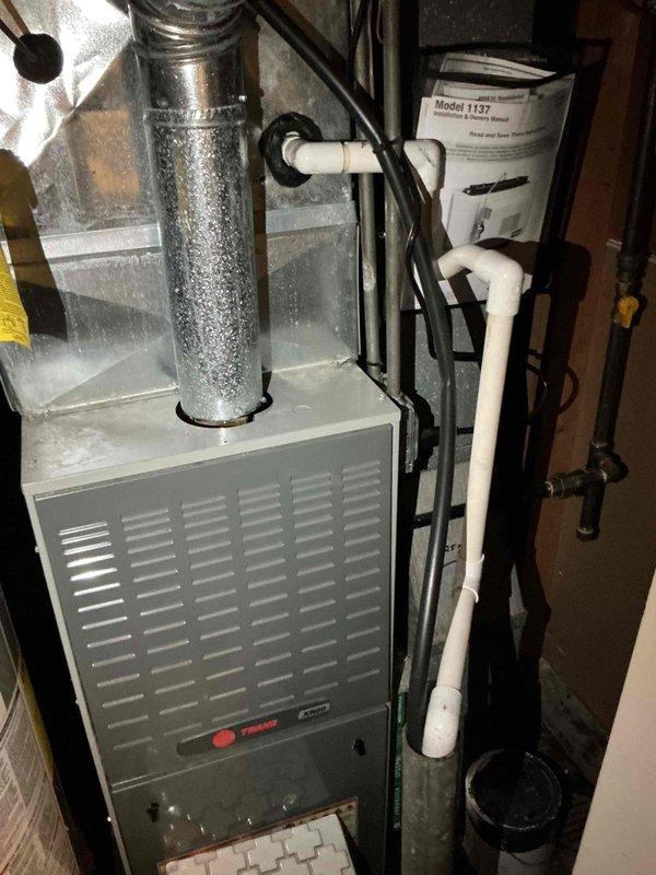 Responded to service call for water accumulation beneath furnace at residential property. Upon arrival, inspected Trane XV95 furnace installation and surrounding mechanical room area. Conducted thorough examination of condensate drainage system, including white PVC condensate lines, drain trap, and discharge piping. Checked for potential sources of water leakage including condensate pump operation, drain line blockages, and proper pitch of drainage pipes. Verified furnace operation and inspected heat exchanger for signs of leakage. Examined water heater proximity to furnace to rule out cross-contamination from plumbing fixtures. Assessed air filter condition and verified proper airflow through system. Inspected all visible piping connections, joints, and elbows for signs of moisture or active leaking. Documented system configuration and equipment condition with photographs for service records.