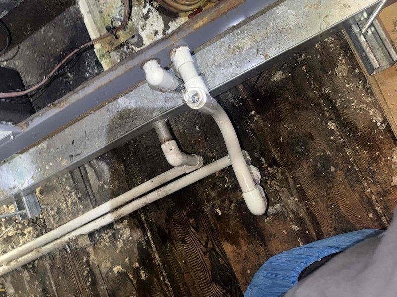 Responded to water leak complaint with moisture visible through bedroom ceiling. Located SpacePak air handler unit in attic and identified active leak from condensate drain system. Upon inspection, found condensate drainage tube discharging water onto attic floor rather than properly routing to exterior drain. Photographed evaporator coil assembly showing significant deterioration of insulation material and confirmed condensate generation from normal system operation. Documented PVC drain line configuration on exterior deck area. Addressed immediate leak concern and provided assessment of system condition including heavily soiled insulation requiring attention.
