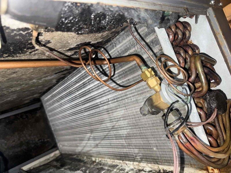 Responded to water leak complaint with moisture visible through bedroom ceiling. Located SpacePak air handler unit in attic and identified active leak from condensate drain system. Upon inspection, found condensate drainage tube discharging water onto attic floor rather than properly routing to exterior drain. Photographed evaporator coil assembly showing significant deterioration of insulation material and confirmed condensate generation from normal system operation. Documented PVC drain line configuration on exterior deck area. Addressed immediate leak concern and provided assessment of system condition including heavily soiled insulation requiring attention.