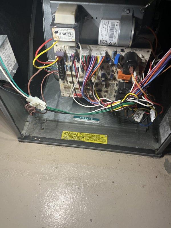 Performed site assessment for residential air conditioning system replacement estimate. Unit is approximately 20 years old and has required multiple repairs during current cooling season. Evaluated existing HVAC system configuration including indoor air handler with blower motor assembly, control board with multi-wire connections, and furnace unit with associated ductwork. Documented exterior condenser location on left side of property. Photographed control panel components, wiring harness connections, refrigerant line routing, and condensate management system to support replacement specifications and equipment sizing recommendations.