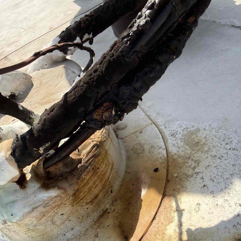 Responded to commercial service call for non-functioning front office air conditioning units. Upon rooftop inspection, discovered catastrophic electrical failure with severely burned and corroded wiring harnesses and electrical components. Extensive fire damage observed on multiple conductors with charred insulation, melted connections, and compromised copper wiring. Documented damage with photographs for insurance and repair authorization purposes. Unit requires complete electrical component replacement and full system evaluation before restoration of service.