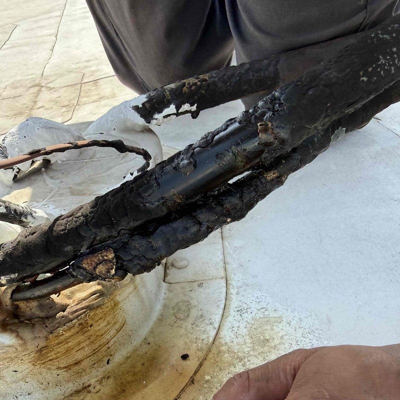 Responded to commercial service call for non-functioning front office air conditioning units. Upon rooftop inspection, discovered catastrophic electrical failure with severely burned and corroded wiring harnesses and electrical components. Extensive fire damage observed on multiple conductors with charred insulation, melted connections, and compromised copper wiring. Documented damage with photographs for insurance and repair authorization purposes. Unit requires complete electrical component replacement and full system evaluation before restoration of service.