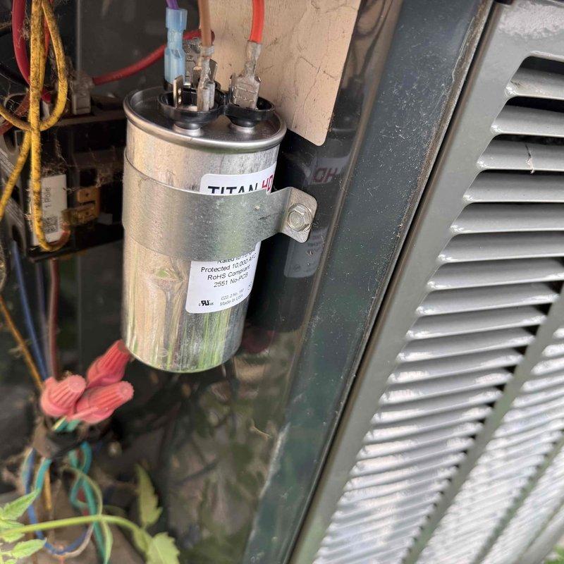 Responded to no cooling complaint with indoor temperature exceeding outdoor ambient. Upon inspection, found failed dual-run capacitor in air handler with visual evidence of bulging and degraded terminals. Replaced defective TITAN capacitor with properly rated unit, restored power, and verified compressor and condenser fan motor operation. System cycled properly with normal amperage draws and temperature differential across evaporator coil. Documented equipment information and discussed preventive maintenance options with customer.