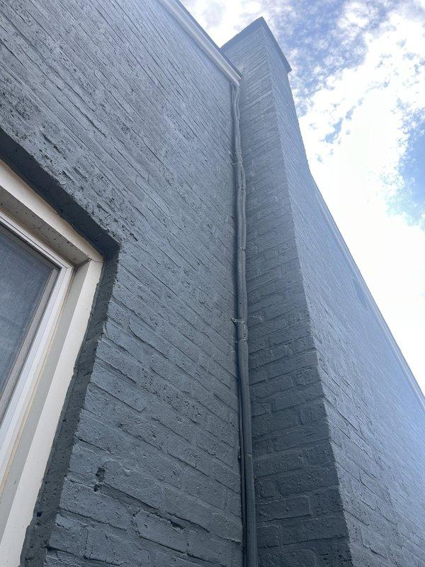 Conducted on-site evaluation for mini-split system installation in attic space. Assessed interior ceiling structure with existing copper refrigerant lines and determined optimal routing for new system components. Evaluated exterior wall penetration points and existing conduit placement along building corner to plan condensate drainage and electrical connections for outdoor condenser unit.