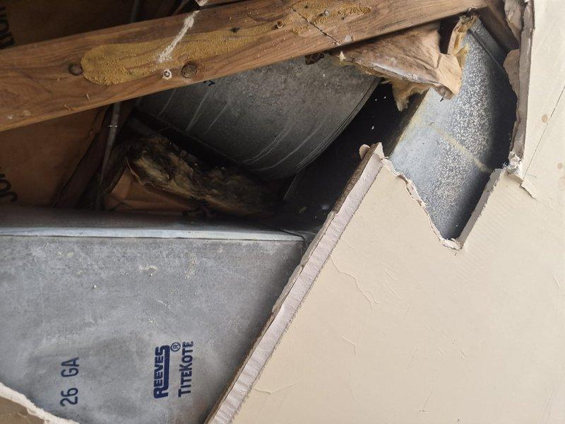 Responded to water leak complaint originating from second floor HVAC unit affecting first floor below. Upon inspection, identified deteriorated drain pan with significant accumulation of debris and biological growth causing water overflow. Examined condensate drain system and flexible coupling connections on unit showing signs of age and wear. Inspected accessible ductwork and structural penetrations in ceiling cavity where leak was occurring. Provided customer education on proper air filter replacement procedures for their system using customer-supplied filters. Documented equipment conditions with photographs showing extent of drain pan deterioration and installation configuration. Recommended drain pan replacement and complete condensate system service to resolve leak issue and prevent future water damage.