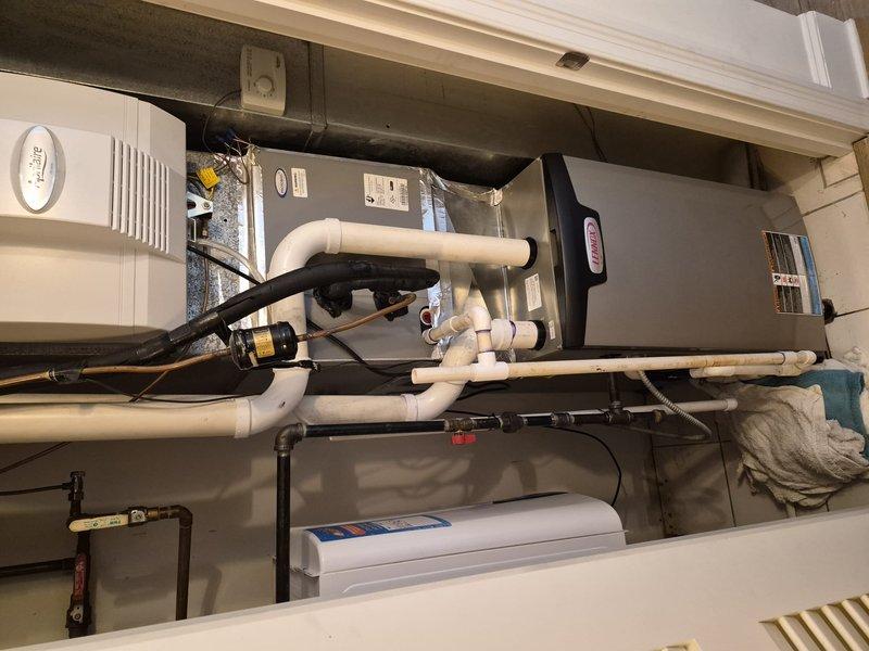 Responded to warranty call for potential condensate line clog and excess condensation from cooling system. Inspected rooftop unit with extended ladder and traced condensate drainage system through mechanical room. Located obstruction in PVC condensate drain line beneath air handler unit. Cleared blockage and installed new flexible drain coupling to restore proper drainage flow. Verified system operation and confirmed condensate removal functioning correctly with no further water accumulation.