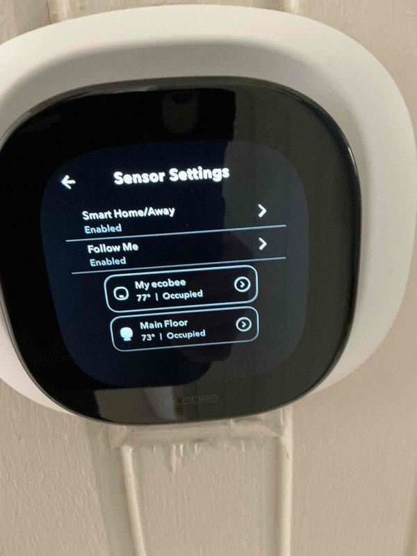 Responded to concern regarding Ecobee smart thermostat displaying incorrect temperature reading of 78°F when actual room temperature was 71°F. Upon inspection, accessed sensor settings menu and identified that thermostat was utilizing multiple remote sensors with "Smart Home/Away" and "Follow Me" features enabled. The main thermostat sensor ("My ecobee") was reading 77-78°F while the "Main Floor" remote sensor was accurately reading 73°F. Adjusted sensor participation settings to prioritize the accurate remote sensor reading and configured the averaging algorithm to provide correct temperature display. Verified system cooling operation was functioning properly and explained to occupant how the multi-sensor system operates and how sensor priority affects displayed temperature. Thermostat now displaying accurate ambient temperature based on optimized sensor configuration.