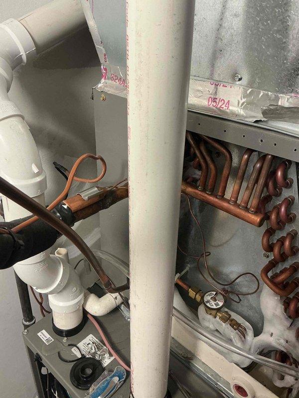Responded to warranty call for water leakage around furnace, humidifier water panel replacement indicator, and metallic rattling noise from unit. Upon inspection, traced water source to condensate drain line issue and cleared blockage in PVC drainage system. Examined evaporator coil assembly and verified proper operation of condensate removal system. Inspected humidifier control panel and confirmed water panel requires replacement per maintenance indicator; advised customer of normal maintenance requirement. Investigated reported metallic rattling noise by examining blower assembly, heat exchanger area, and mechanical components within furnace cabinet. Identified loose mounting hardware on blower motor assembly causing vibration and noise; tightened all fasteners and verified secure mounting. Checked refrigerant lines and copper piping connections for proper support and insulation. Tested system operation through complete heating cycle to confirm resolution of all reported issues. Veri