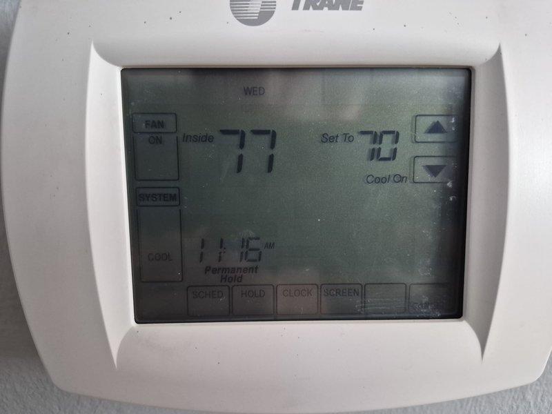 Responded to no cooling call on approximately 2-year-old Trane system. Upon arrival, found thermostat calling for cooling with setpoint at 70°F while indoor temperature read 77°F. Performed diagnostic testing at indoor unit using clamp meter to check electrical amperage draw and system operation. Verified thermostat display showing permanent hold with system in cooling mode. Documented equipment information and captured diagnostic readings for service records.